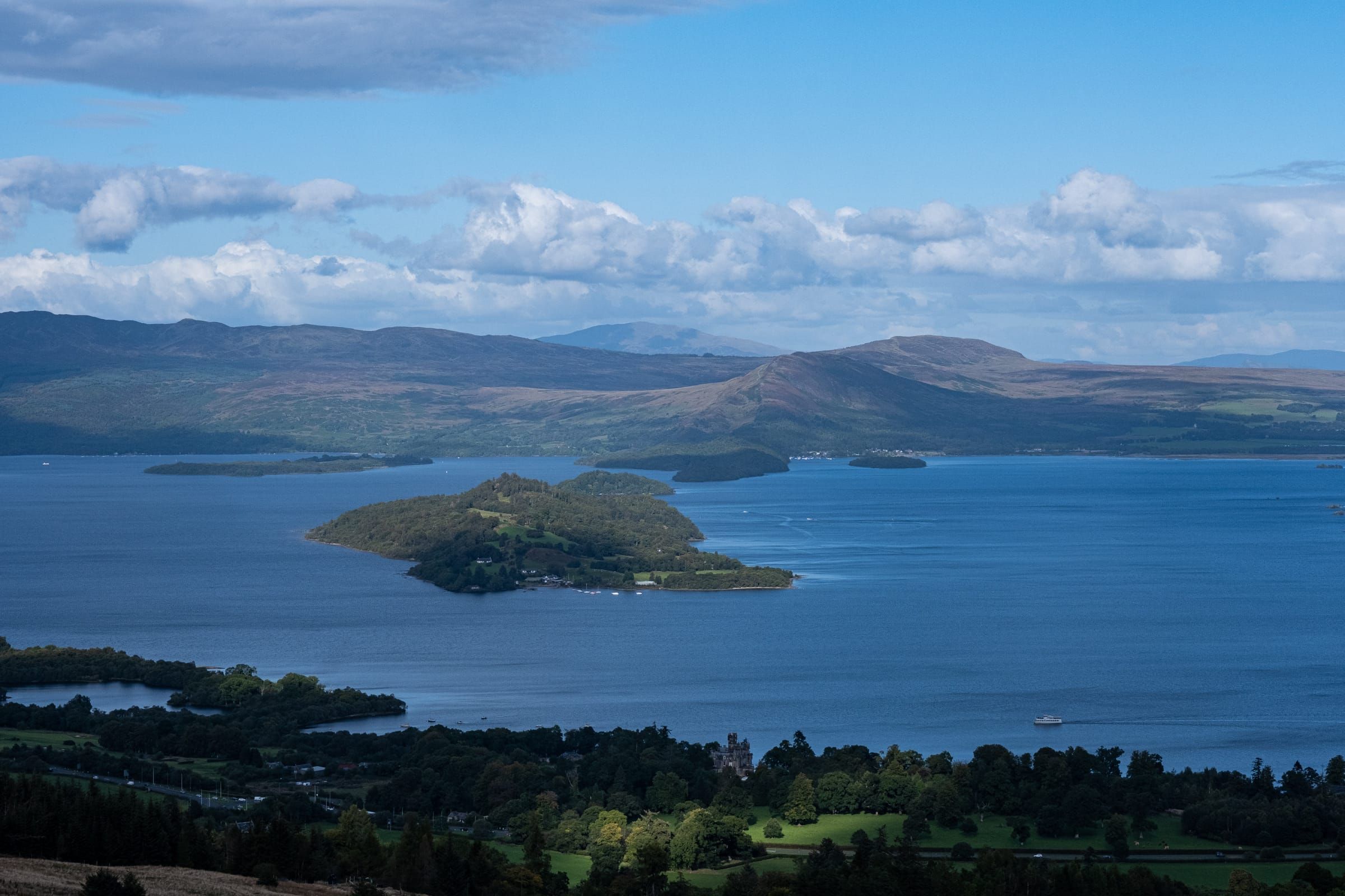 View of Loch Lomond in Scotland with a water bus heading towards a tiny island.